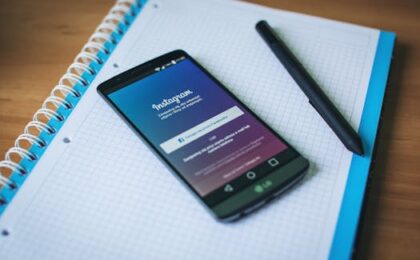 A smartphone displaying Instagram on a notepad with a pen, symbolizing social media and productivity.